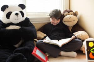 boy reading beside stuffed panda and brown bears