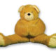 A large, plush teddy bear sitting with its legs spread wide.