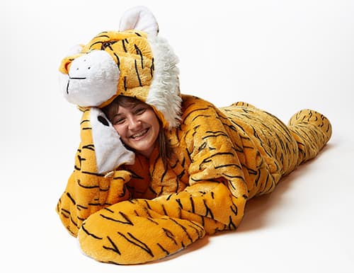 woman laying down in snoozoo plush tiger sleep sack